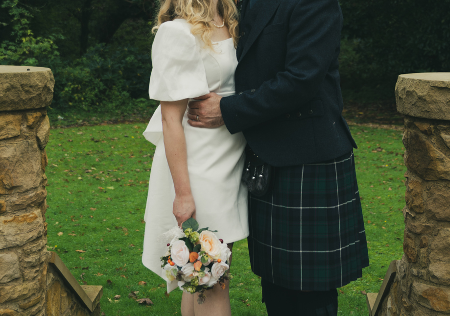 Autume wedding image, couple kissing outdoors, kilt, wedding dress, and flowers